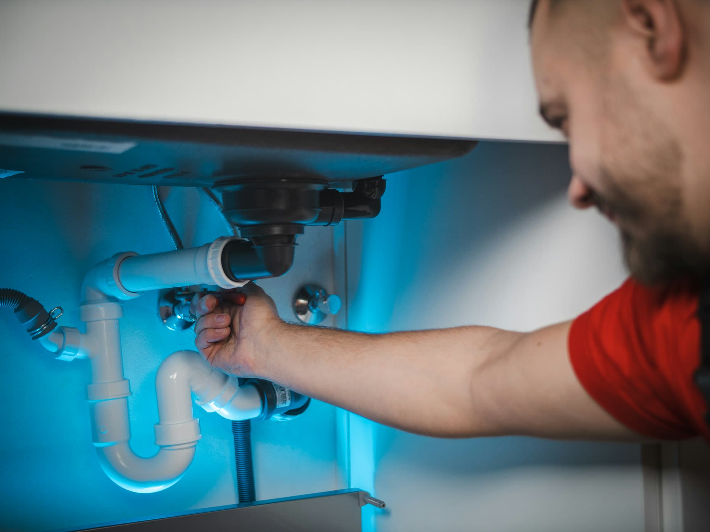 A plumber cutting into a wall to reach a failed pipe