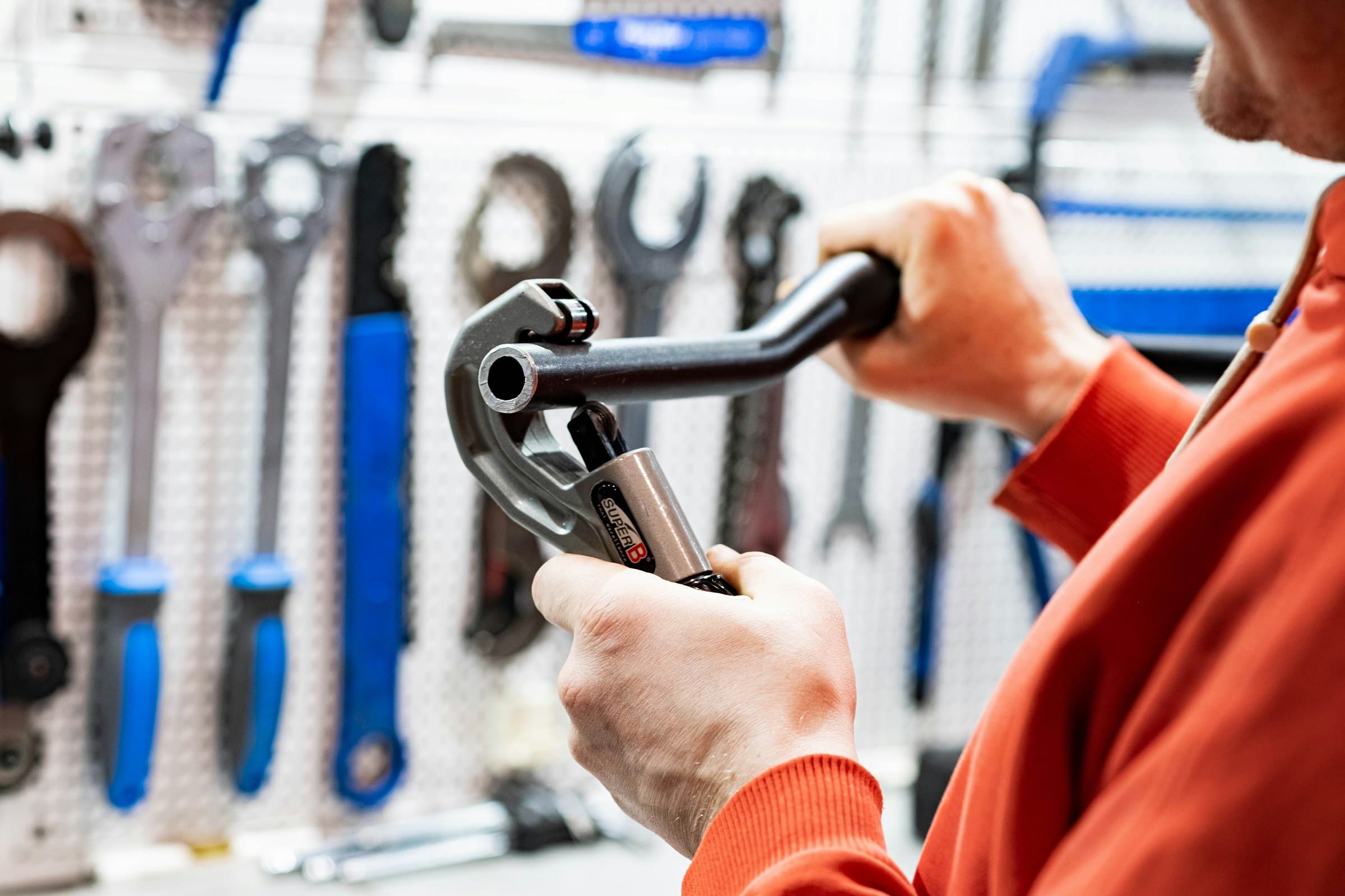 A plumber holding a wrench in front of a wall of tools